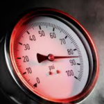 Close-up of a circular pressure gauge reading about 90 psi, with a red glow and a dark center knob.