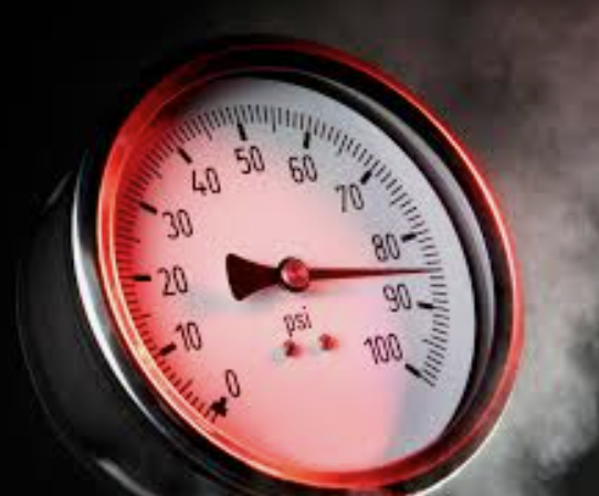 Close-up of a circular pressure gauge reading about 90 psi, with a red glow and a dark center knob.